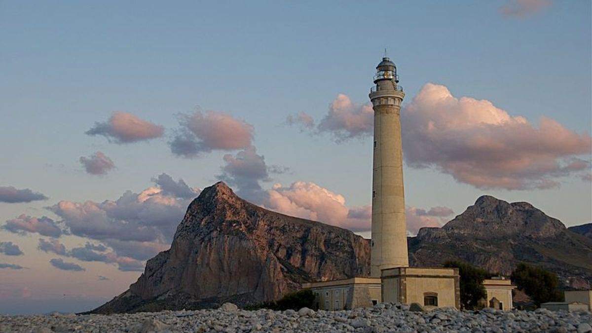 Faro di Capo di Santa Croce, uno dei più belli d'Italia, illuminato al tramonto.