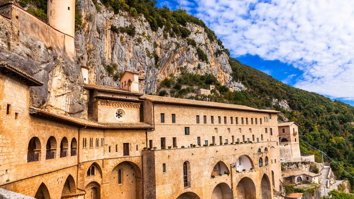 Monastero nascosto tra le montagne italiane, circondato da natura lussureggiante e un'atmosfera mistica.