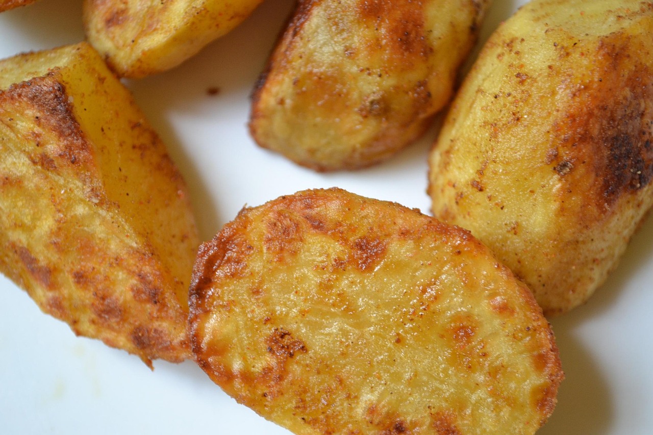 Patate al forno dorate e croccanti, servite su un piatto con erbe aromatiche.