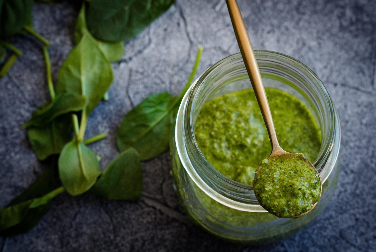 Vasi di pesto di diverse marche con etichette evidenziate in un supermercato.