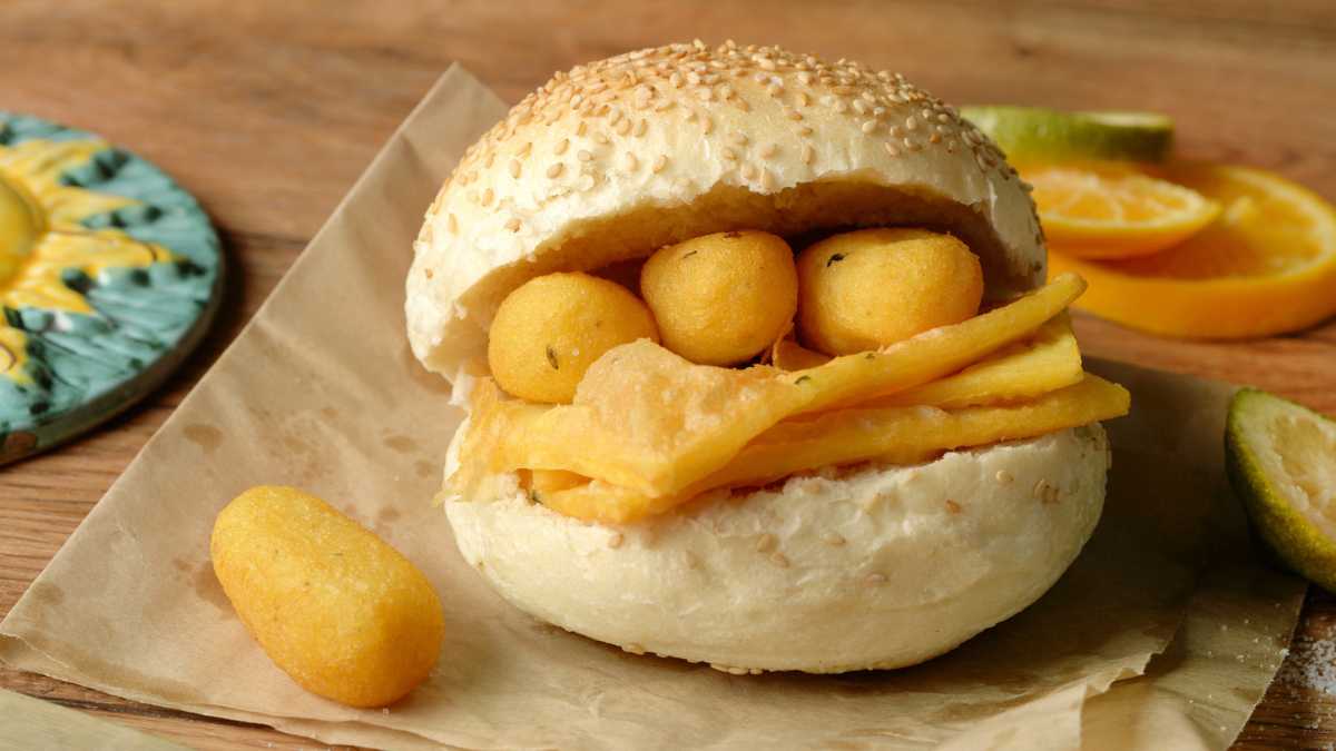 Un piatto di arancini siciliani su un tavolo di legno, tipico street food siciliano.
