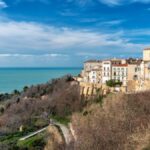 Panorama di un borgo nascosto nelle Marche, con fiori primaverili e architettura storica.