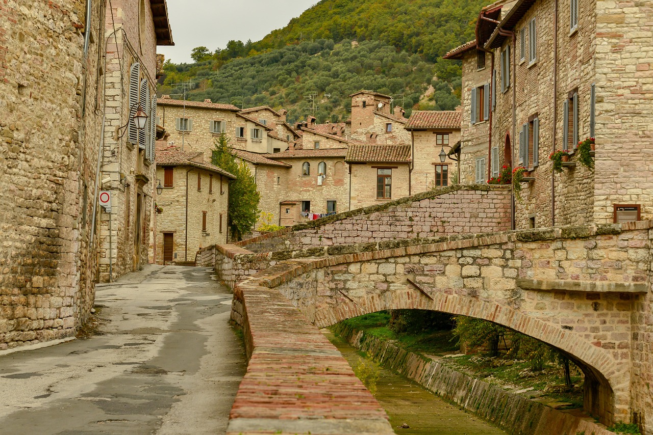 Borgo umbro diviso da un torrente, con passerella di legno che collega le due sponde.