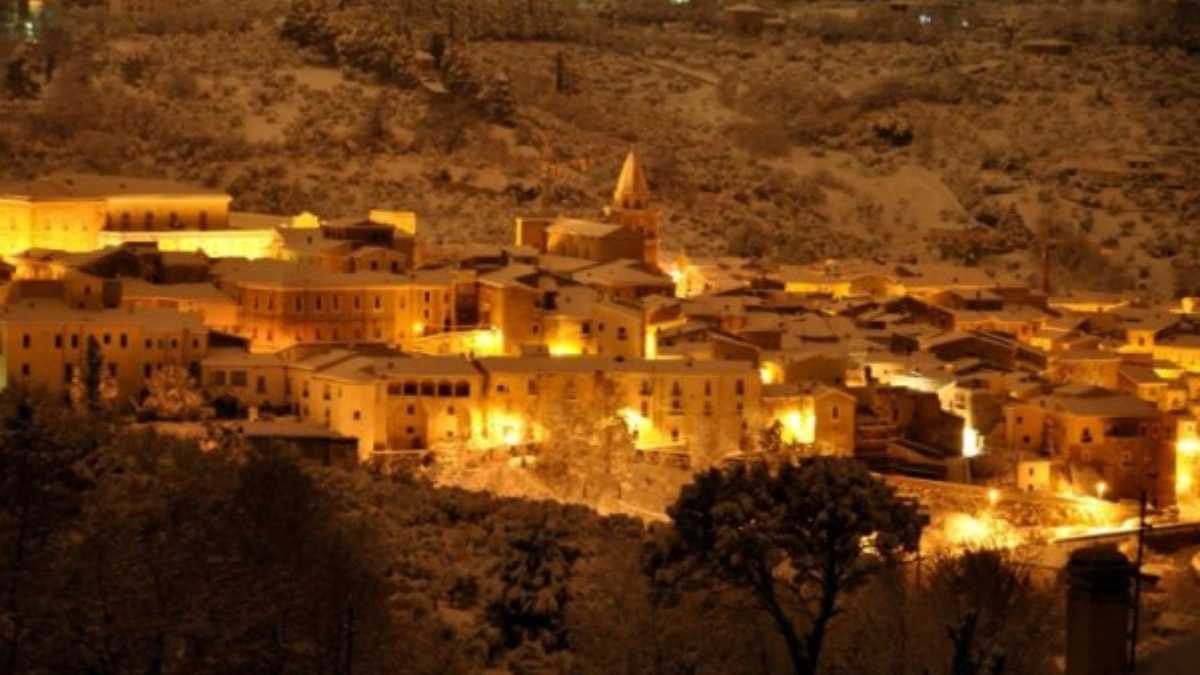 Borgo pittoresco con case colorate e paesaggio montano, simbolo della cultura italiana all'estero.