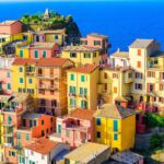 Borgo ligure con case colorate simili a Burano, vista pittoresca tra mare e montagne.